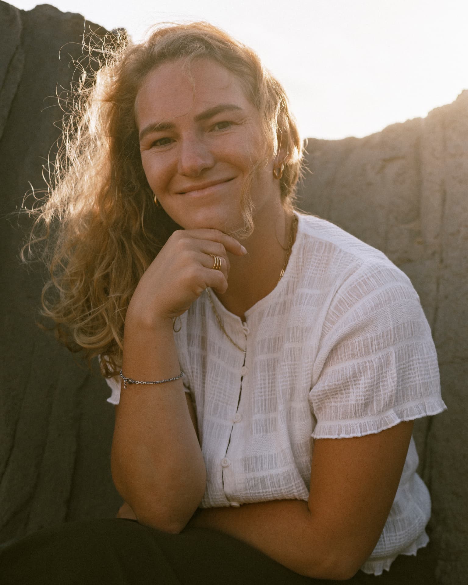 Elena Kochler smiling in golden evening light against a sandstone wall