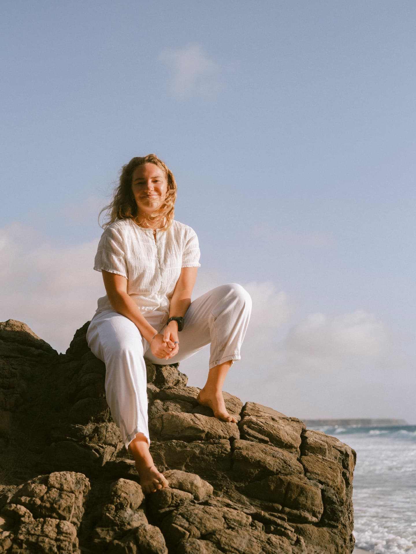 Elena sitting on coastal rocks looking out over the water