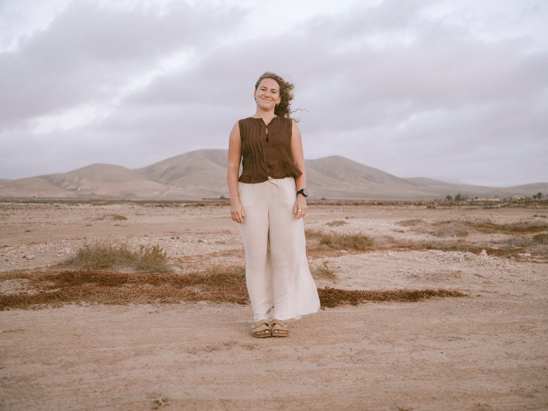 Elena standing in a wide desert landscape with volcanic hills behind her